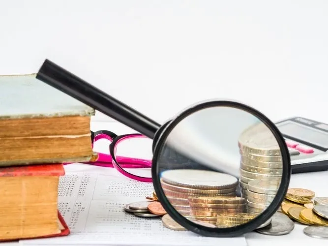 Financial analysis with coins and magnifier